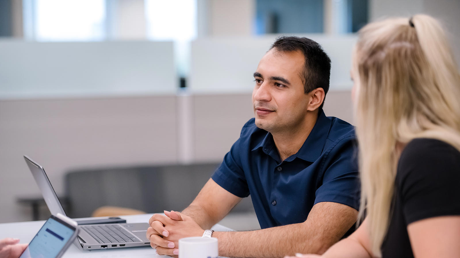 a person and person sitting at a table with a laptop