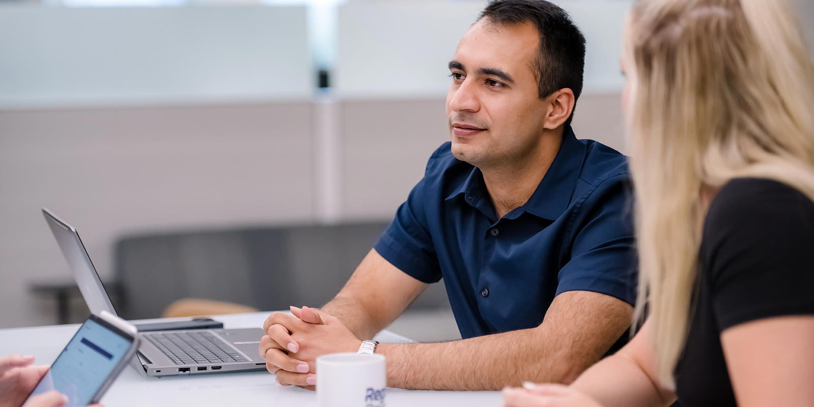 a person and person sitting at a table with a laptop
