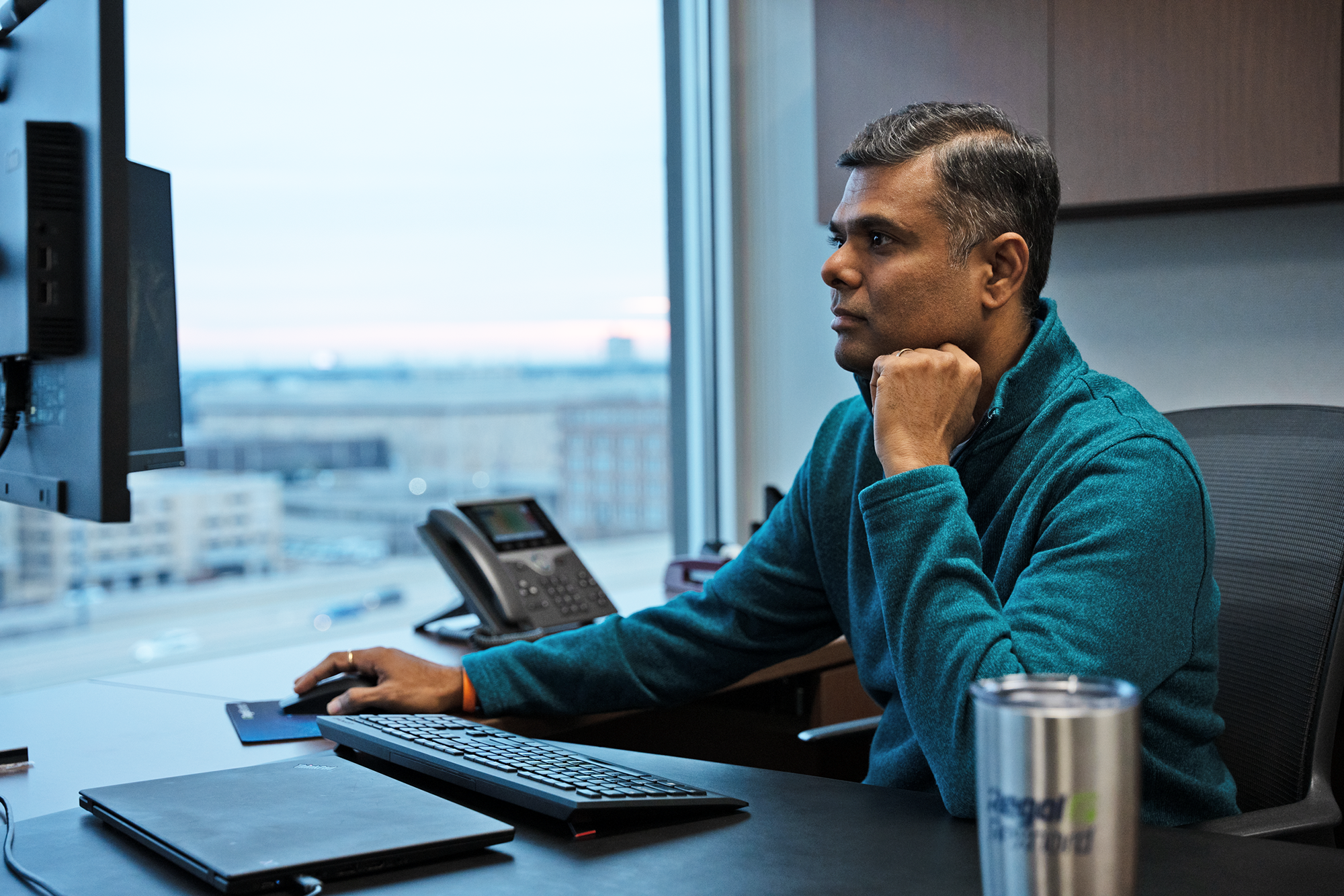 a person sitting at a desk with a computer and a phone