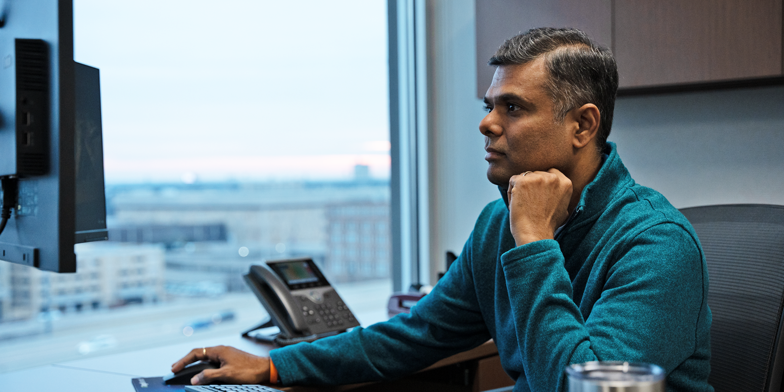 a person sitting at a desk with a computer and a phone