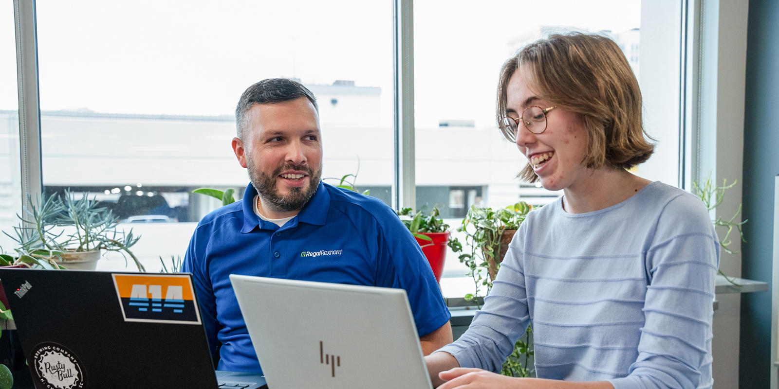 a person and person sitting at a table with laptops